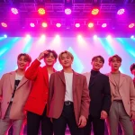 BTS members performing passionately on stage during a vibrant concert event.